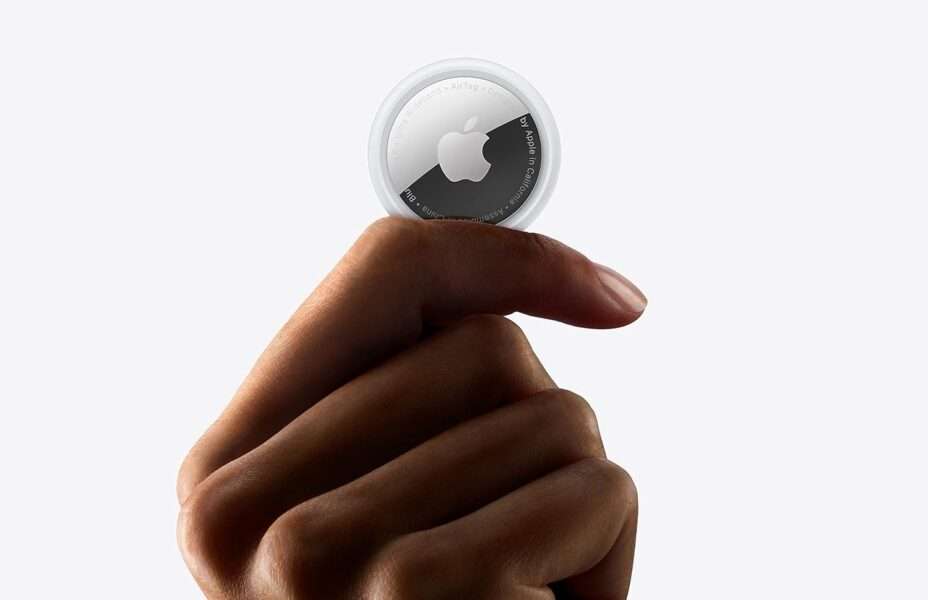 Apple AirTag is held in a persons hand for size comparison.