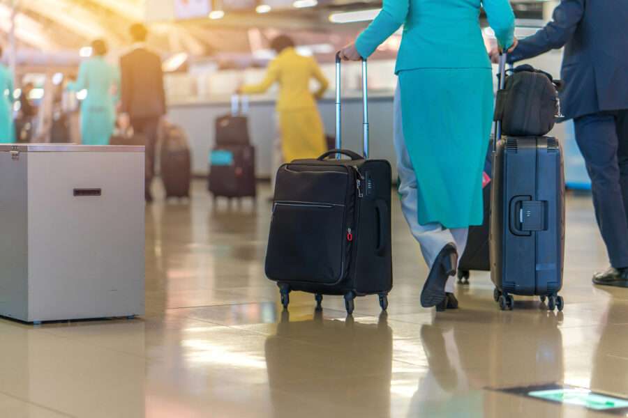 Airline Crew and Passengers at an Airport all with carry-ons.