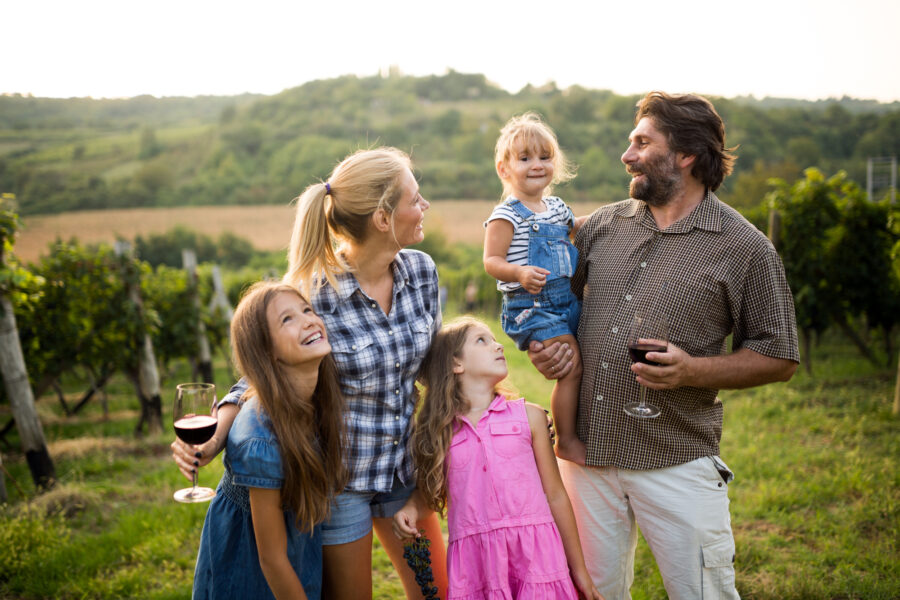 A happy family spending time in a vineyard together - Family Vacation Overseas