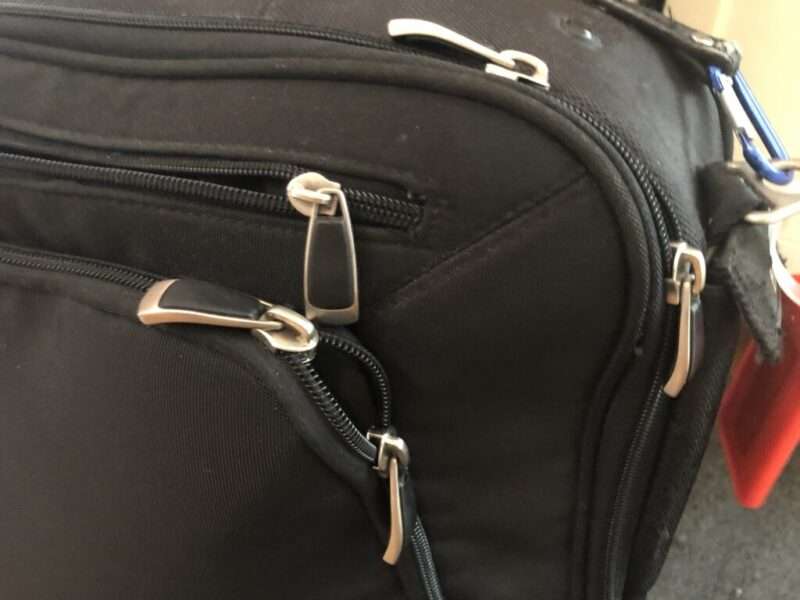 A well worn carry on with multiple zips and zip pulls.